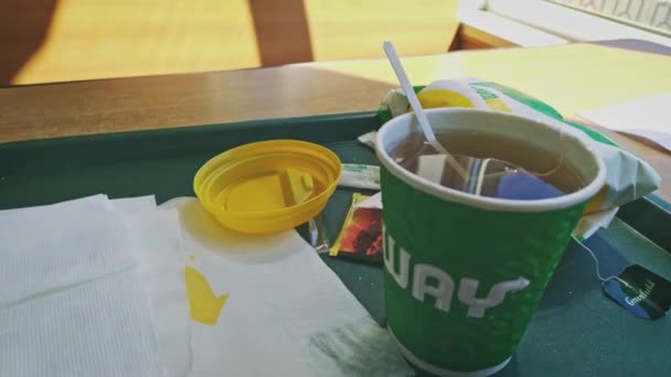 Astrakhan Russie, 11 novembre 2019 : Nourriture du métro. Tasse à thé ouverte avec sachet de thé sur plateau avec sous-sandwich enveloppé dans du papier de marque. — Video