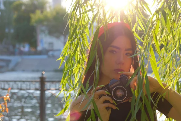 日落时分 可爱的亚洲姑娘手握古旧的电影摄影机 在柳枝上摆姿势 古色古香的浪漫照片 — 图库照片