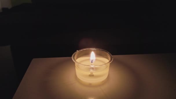 Vela decorativa de cera puesta en la mesa en la oscuridad — Vídeo de stock