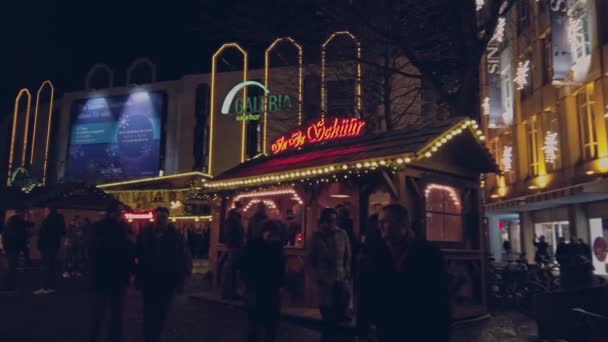 Bonn Germany, 23 Dec. 2019: Christmas crowd pan shot. Many people walk along the garlanded stalls of the Christmas market 4k 60fps slow motion. — Stockvideo