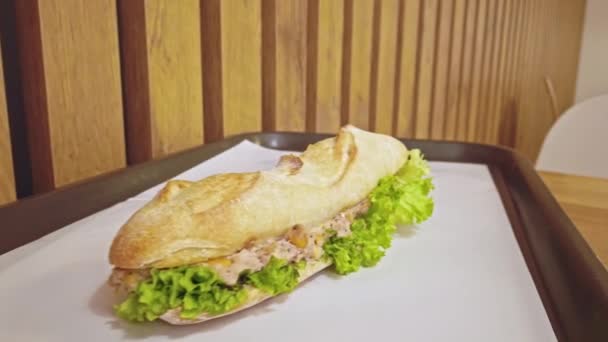 Mouthwatering tuna sandwich with salad leaves inside served on tray — Stock video