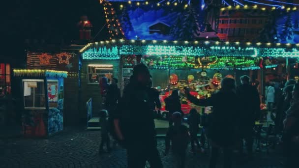 Bonn, Germany,14 of Dec., 2019: Christmas market in the nighttime, children ride the carousel while other people walk by — Stockvideo