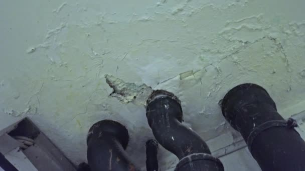 Sewer pipes mounted on celling with leaks on plaster — Stockvideo