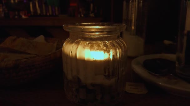 Świeca w słoiku. Dekoracyjna świeca woskowa ustawiona na stole w ciemności — Wideo stockowe