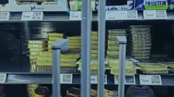 Bonn,Germany, 14 of Dec.,2019:interior shot of REWE supermarket POV. A man in fingerless gloves takes a packet of sliced cheese from the fridge.Its the exclusive brand Ja belongs to the REWEnetwork — Αρχείο Βίντεο