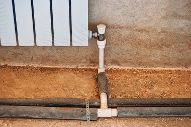 Yeraltı ısıtma boruları, alçıyla kaplanmış duvar kenevirine bağlanmış. Isıtma sistemi. Boru tesisatçısı ısıtma borularını yerleştiriyor. Sıcak suyla ısıtma sistemi