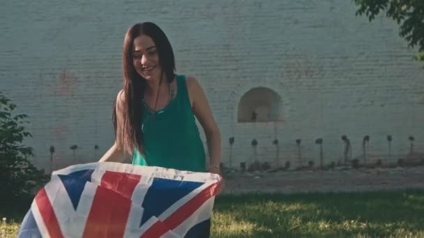 Молодая женщина играет с Великим британским флагом на открытом воздухе в летний день — стоковое видео