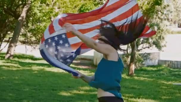 Joyeux jeune femme tenant drapeau des États-Unis dans l'air et tournant au ralenti — Video