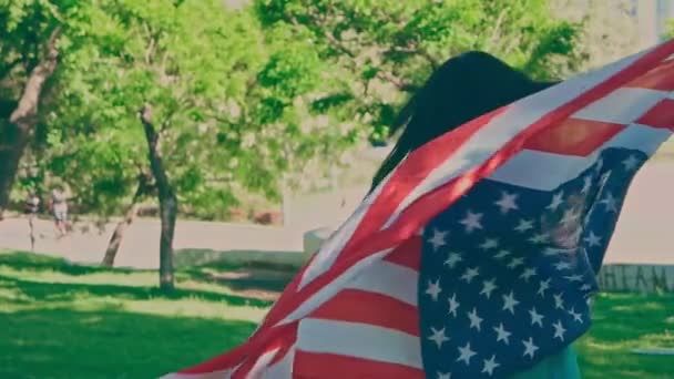 Молодая женщина поворачивается в замедленной съемке, держа американский флаг — стоковое видео