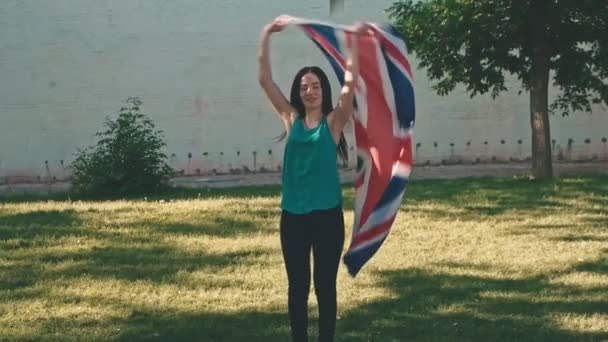 Jeune femme agitant un grand drapeau britannique en slomo — Video