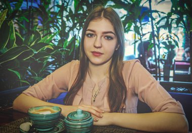 Kafeteryada oturan ve kameraya bakan çok ciddi bir kadın. Kahve molası.