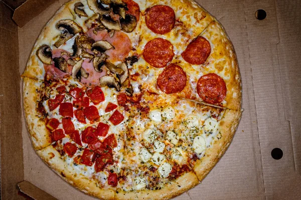 Pizza entière dans une boîte sur une surface en carton. Vue du dessus. — Photo