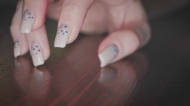 Kız tırnaklarını cilalı tezgahta egzotik manikürle okşuyor.