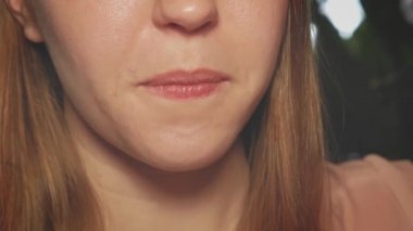 Dilini çıkaran bir kadın, yüzünün bir kısmı sarışın kız..