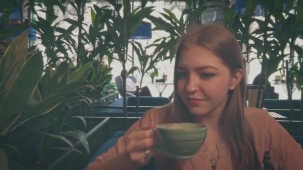 Jeune fille slurs à partir d'une tasse de café dans un café — Video