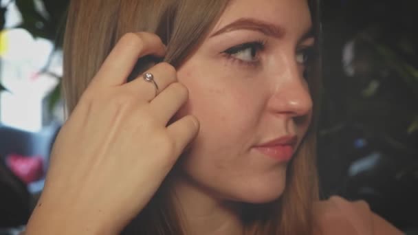 A girl with a smile looks into the camera after she threw her hair from her cute ear — Stock Video