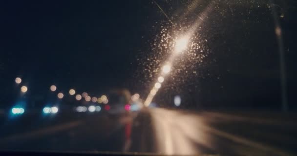 비오는 밤에 차를 타고 가면서 먼지가 많은 앞 유리를 통해 흐린 고속도로를 바라봄 — 비디오