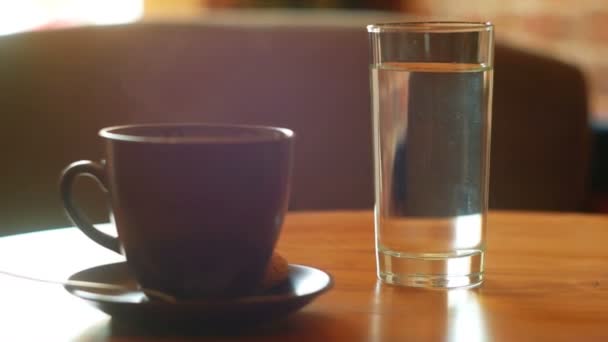 Kopp kaffe och glas vatten på bordet — Stockvideo