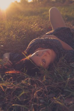 Güzel gülümseyen esmer bayan parktaki çimlerde dinleniyor..