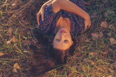Young nice lady lying on grass with her eyes closed, ripe lips open and hands crossed..