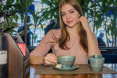 Genç bayan bir kafeteryada oturuyor. Bir kafede dinlenen mutlu sarı saçlı kadın..