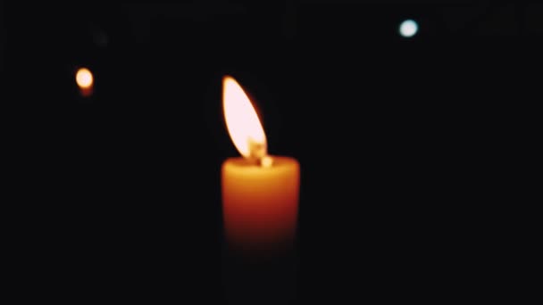 Una vela borrosa brillando en la habitación oscura — Vídeos de Stock