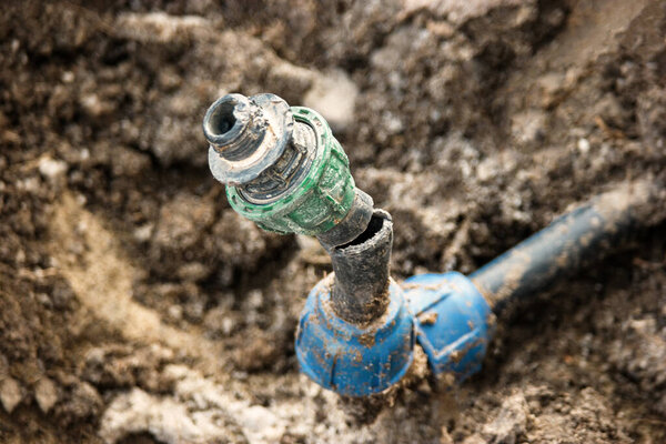 Repair and fixing concept. Broken punctured plastic water pipe in back yard ditch nedds repair.