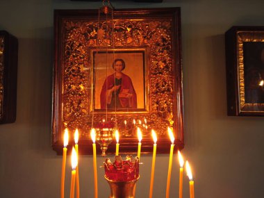 Astrakhan Rusya - 10 Ekim 2020: İçerideki Ortodoks Kilisesi, altın tezgahta yanan mumlarla süslenmiş Aziz ikonu önünde altın çerçeveyle süslenmiş.