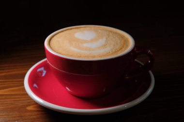 Red Cup of coffee in dark room on desk