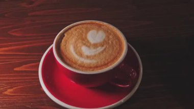 Masanın üzerinde kırmızı bir fincan kahve var.