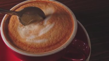 Kırmızı kahve fincanı kaşıkla ağır çekimde karıştırılmış.