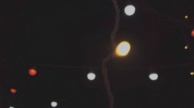 Gökyüzünün önündeki ışık süslemesi. Koyu arkaplanın önünde hareket eden bir ampul. Depresyon. Parti bitti..