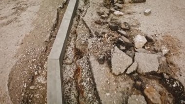 Yaya geçidi için kaldırım taşının yan tarafına yerleştirilmiş. Yıkılmış asfaltı seyrederek yürüyorum. Yeniden yapılanma alanı.