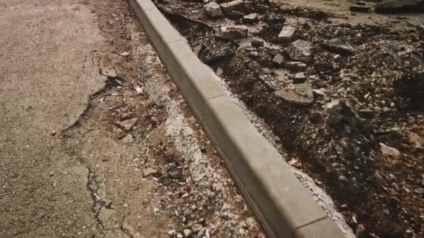 POV dari curbstone yang baru dipasang dengan puing-puing disisihkan tetap dengan beton — Stok Video