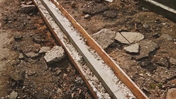 The new curbstone is mounted in a wooden formwork and is filled with fresh concrete — Vídeo de stock