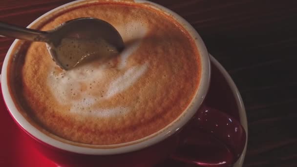 Taza de café rojo en la mesa mezclado por cuchara en cámara lenta — Vídeo de stock