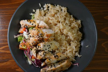 Spicy chicken on stir rice with salad and vegetables top view.