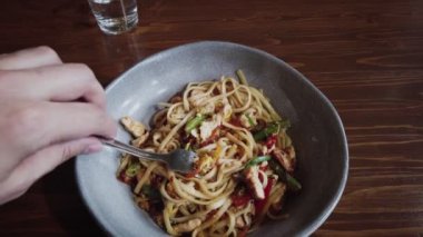 man winds noodles on a fork dolly in shot in slow motion