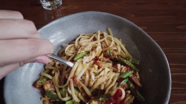Dolly skott av man äter udon pasta nudlar i bwl, fokusera på gaffel med slingrade nudlar — Stockvideo