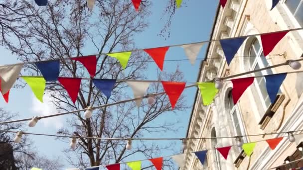 도시의 거리 위로 날아가는 밧줄에 걸려 있는 많은 삼각형 깃발 장식 — 비디오