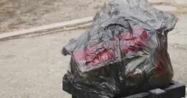 Trash packed in black plastic bag overfilled street trash bin on wind