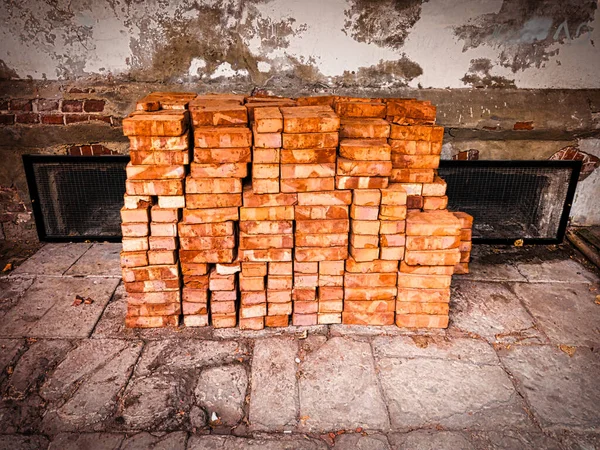 Stack of red bricks in front of weathered wall — Stock Photo, Image