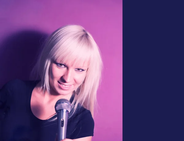 Styl życia młodych ludzi pojęcie: Blond modelka piosenkarka z mikrofonem na różowym tle z copyspace — Zdjęcie stockowe
