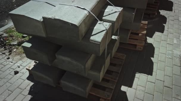 Městské kameny připraveny k instalaci. Betonové obrubníky na dřevěných paletách stojí na povrchu ulice při opravě ulice. Oprava silničních prací — Stock video