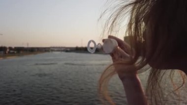 Sabun köpüklerini nehire yavaş çekimde üfleyen bir kız.