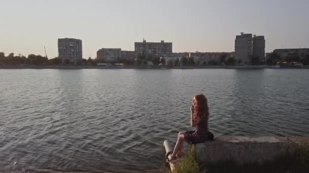 Junge süße Dame tagträumt, während sie auf Betonbrüstung Stadt Waterfront sitzt — Stockvideo