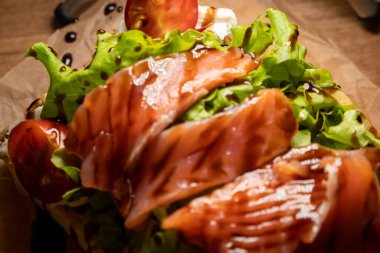 Dilimlenmiş tuzlu somon, domates ve salata yapraklı Belçika waffle 'ı..