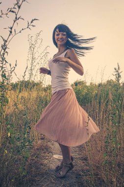 Romantik bir kadın, siyah saçlarıyla tarlalarda dans ediyor, havada uçuyor, bulanık hareketli çekim yapıyor..