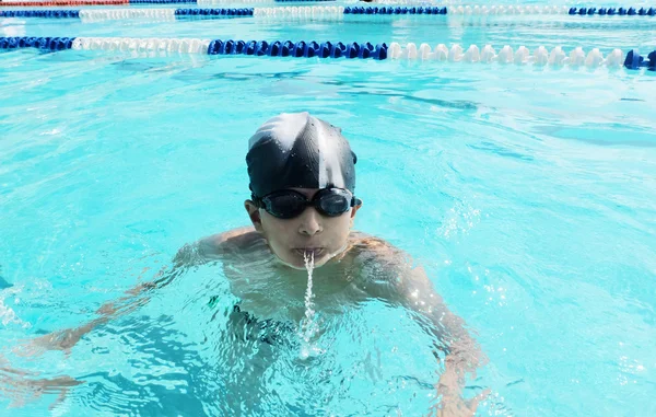 Pojke i pool spiting ut en ström av vatten — Stockfoto