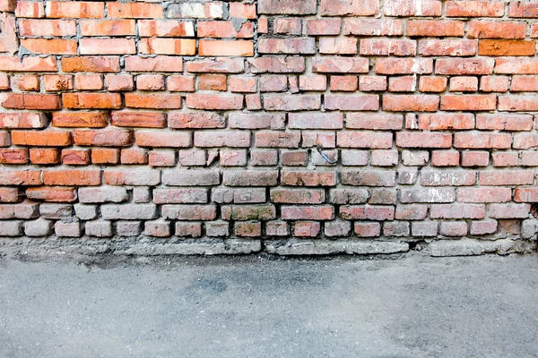 Kırmızı tuğla duvar ve bir asfalt — Stok fotoğraf